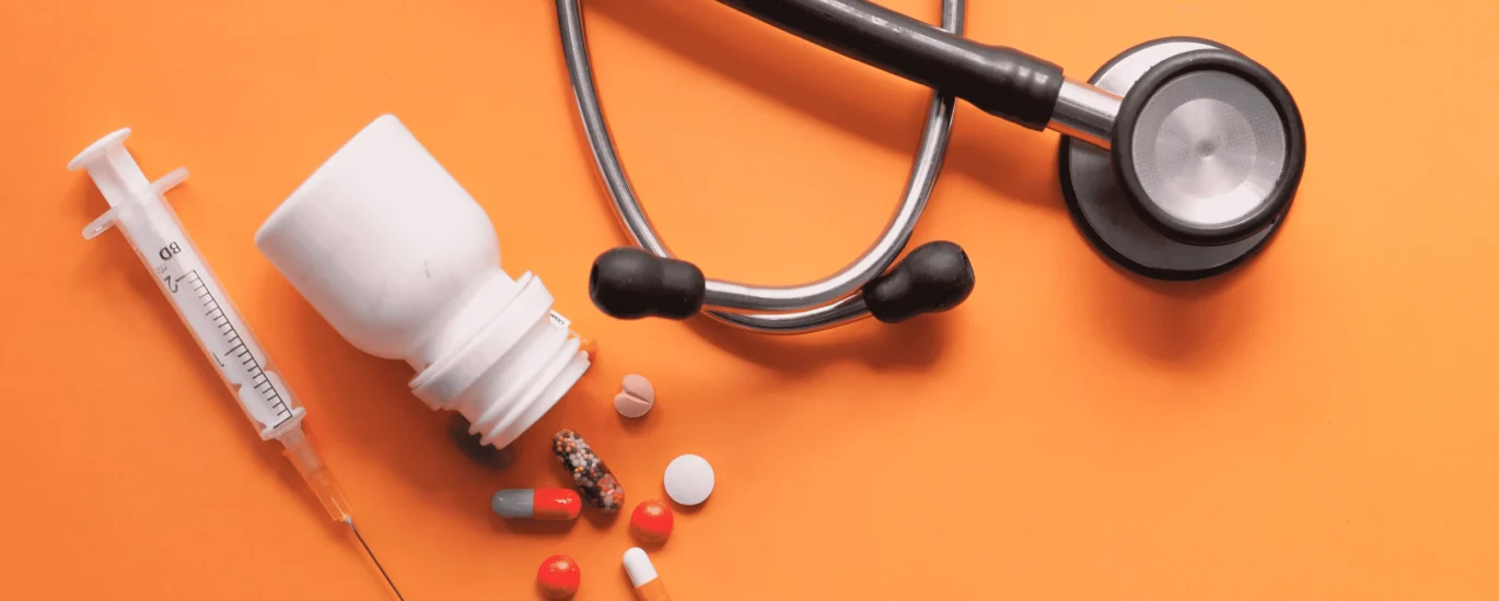 Assorted medication tablets and capsules in various colors on a white background.